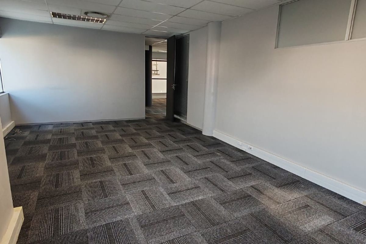 A vacant office space featuring neutral walls, carpet tile flooring, and a suspended ceiling with recessed lighting.