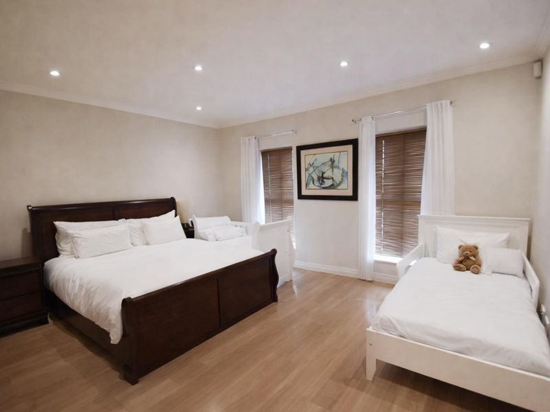 Spacious bedroom featuring laminate flooring, recessed downlighting, and timber venetian blinds, offering a neutral and well-maintained living space.