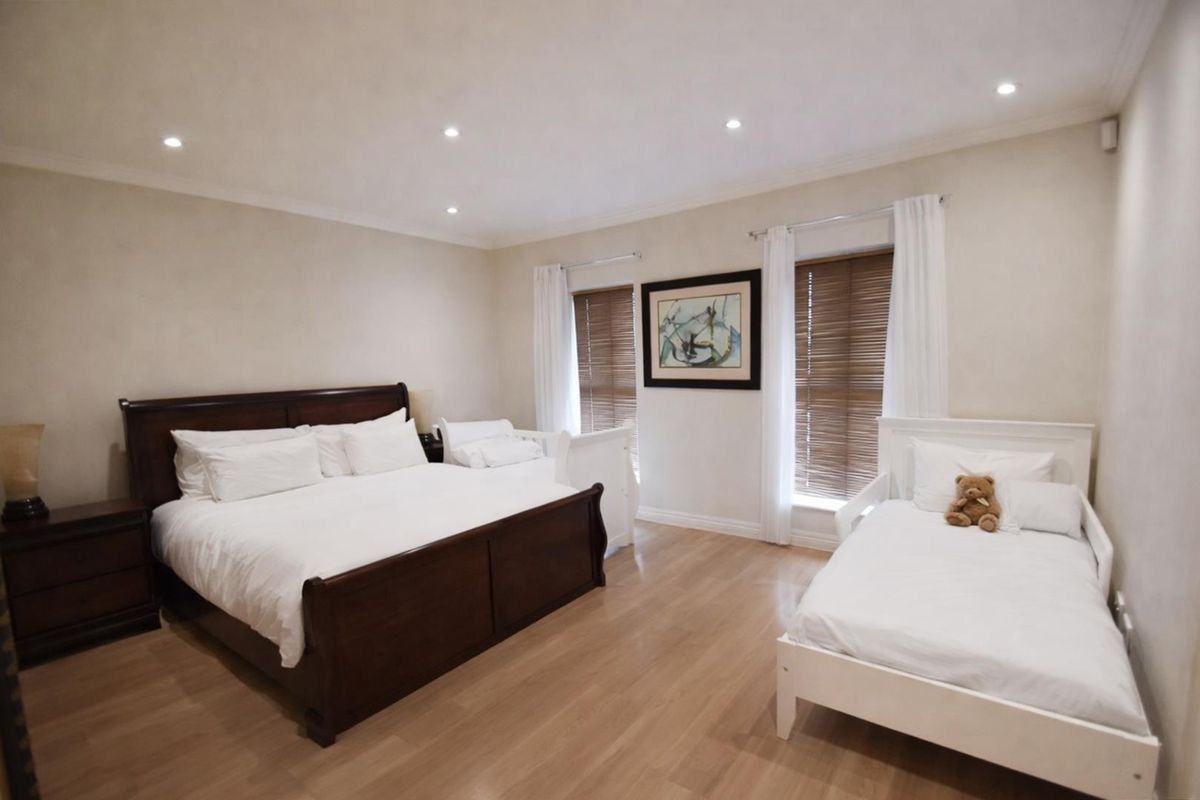 Spacious bedroom featuring laminate flooring, recessed downlighting, and timber venetian blinds, offering a neutral and well-maintained living space.