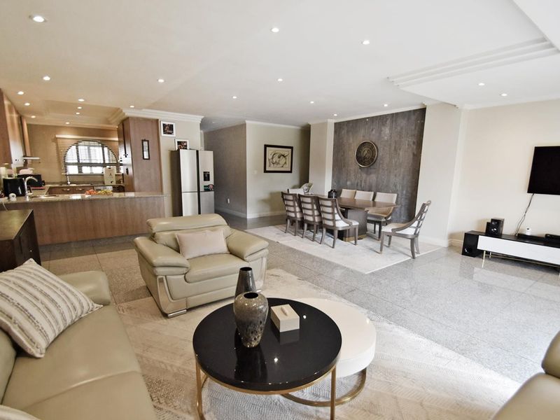 Spacious open-plan living and dining area featuring polished stone tile flooring, recessed lighting, and a modern kitchen with integrated cabinetry.