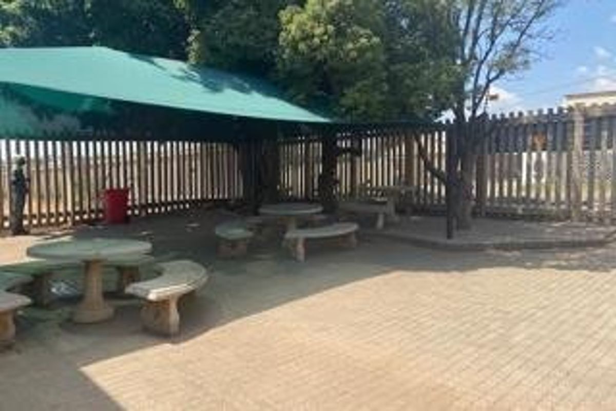 Outdoor paved patio area featuring a large shade sail covering, providing a functional space for commercial or communal use.