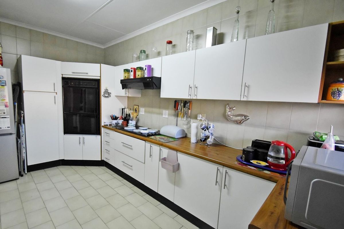 A functional kitchen featuring white cabinetry, wood-look laminate countertops, a built-in oven, and tiled backsplash with neutral floor tiles.