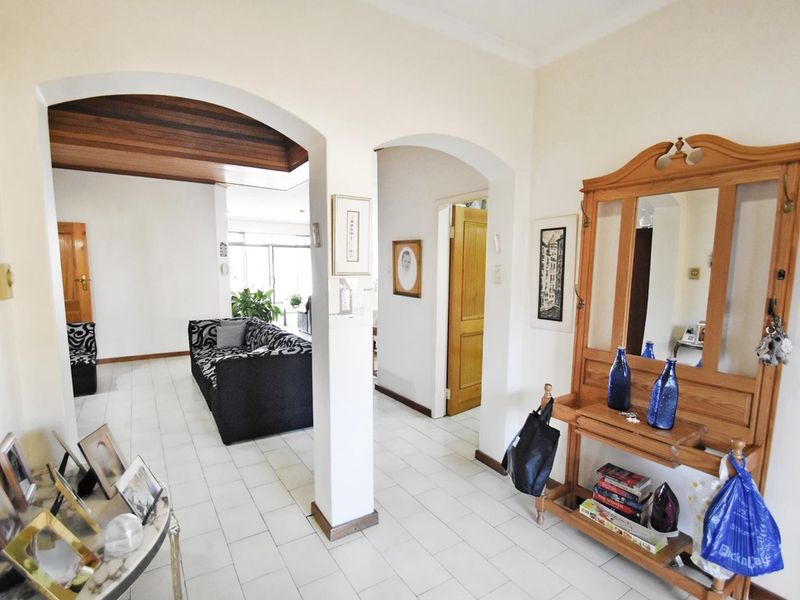 A bright entrance hallway featuring tiled flooring and distinctive arched doorways leading into the main living areas of the apartment.