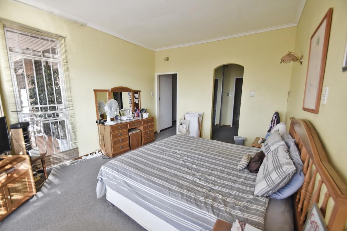 A bedroom featuring carpet flooring, an arched doorway, and a sliding glass door providing access to an outdoor area.