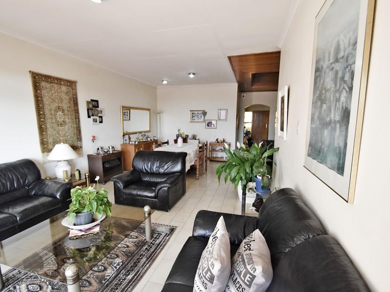 Spacious open-plan living and dining area featuring neutral tiled flooring and recessed lighting, offering a versatile layout for comfortable family living.