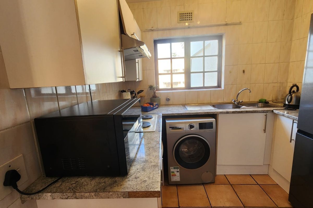 Compact kitchen featuring tiled backsplash, laminate countertops, built-in cabinetry, and a functional layout with space for integrated appliances.