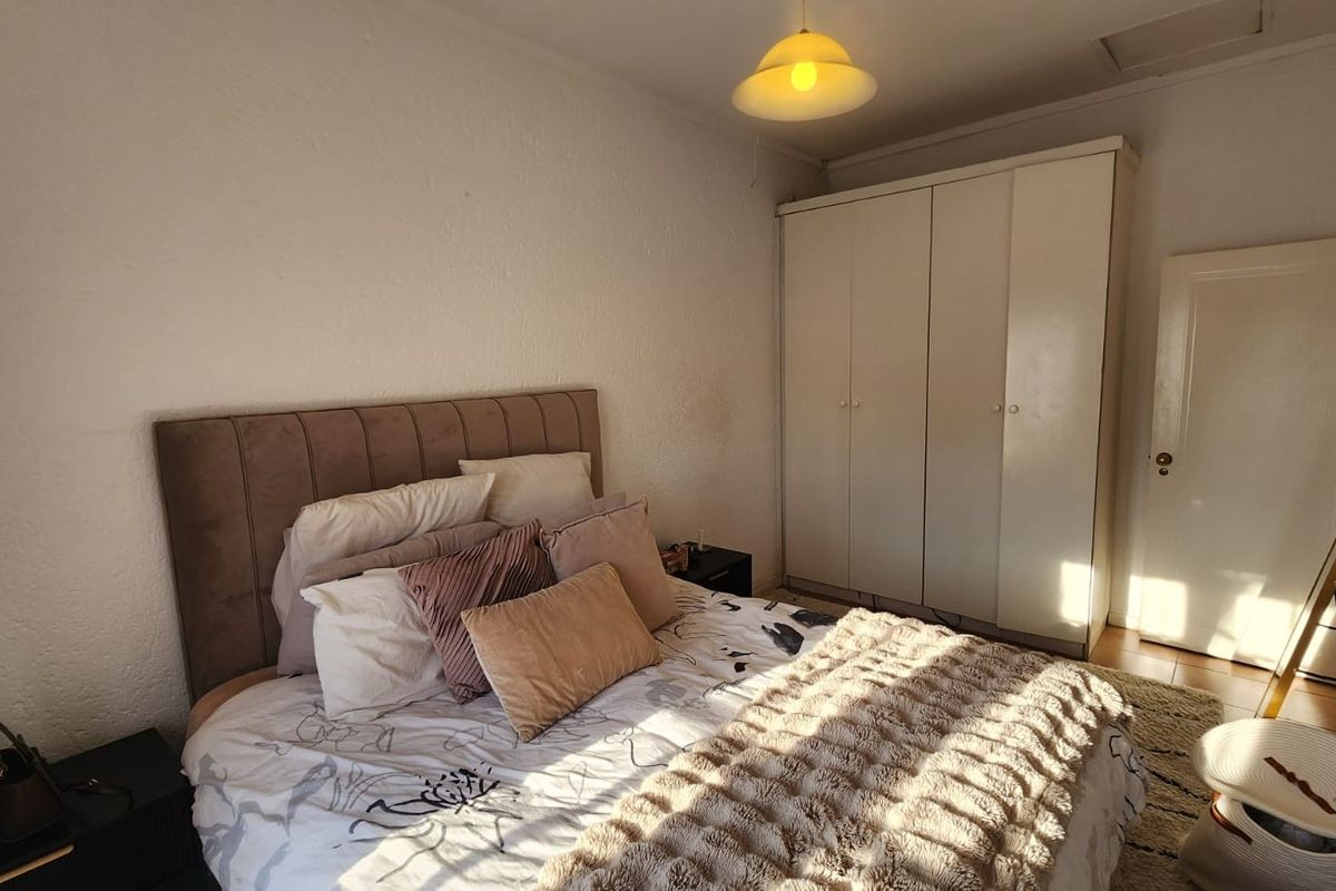 A functional bedroom featuring a built-in wardrobe and neutral wall finishes, offering a comfortable space with potential for cosmetic updates.