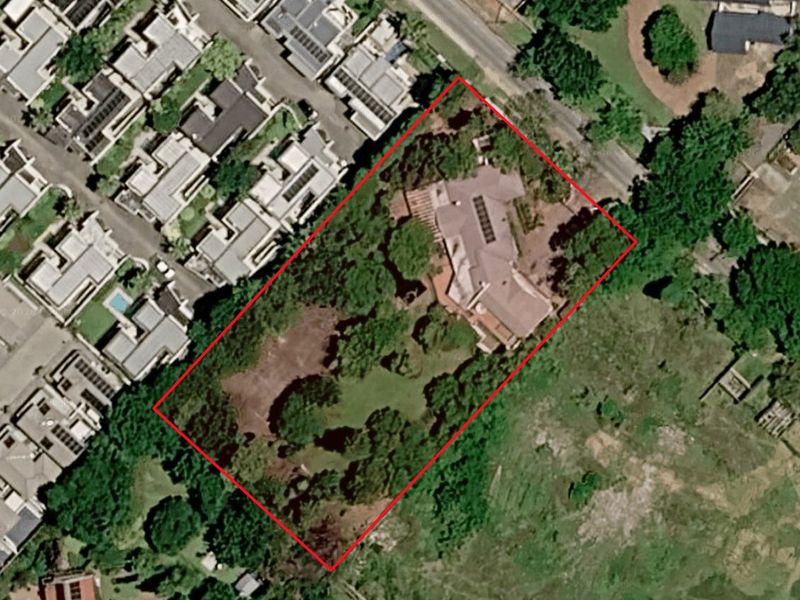 Aerial view of a residential property featuring a large garden with mature trees and a central dwelling.