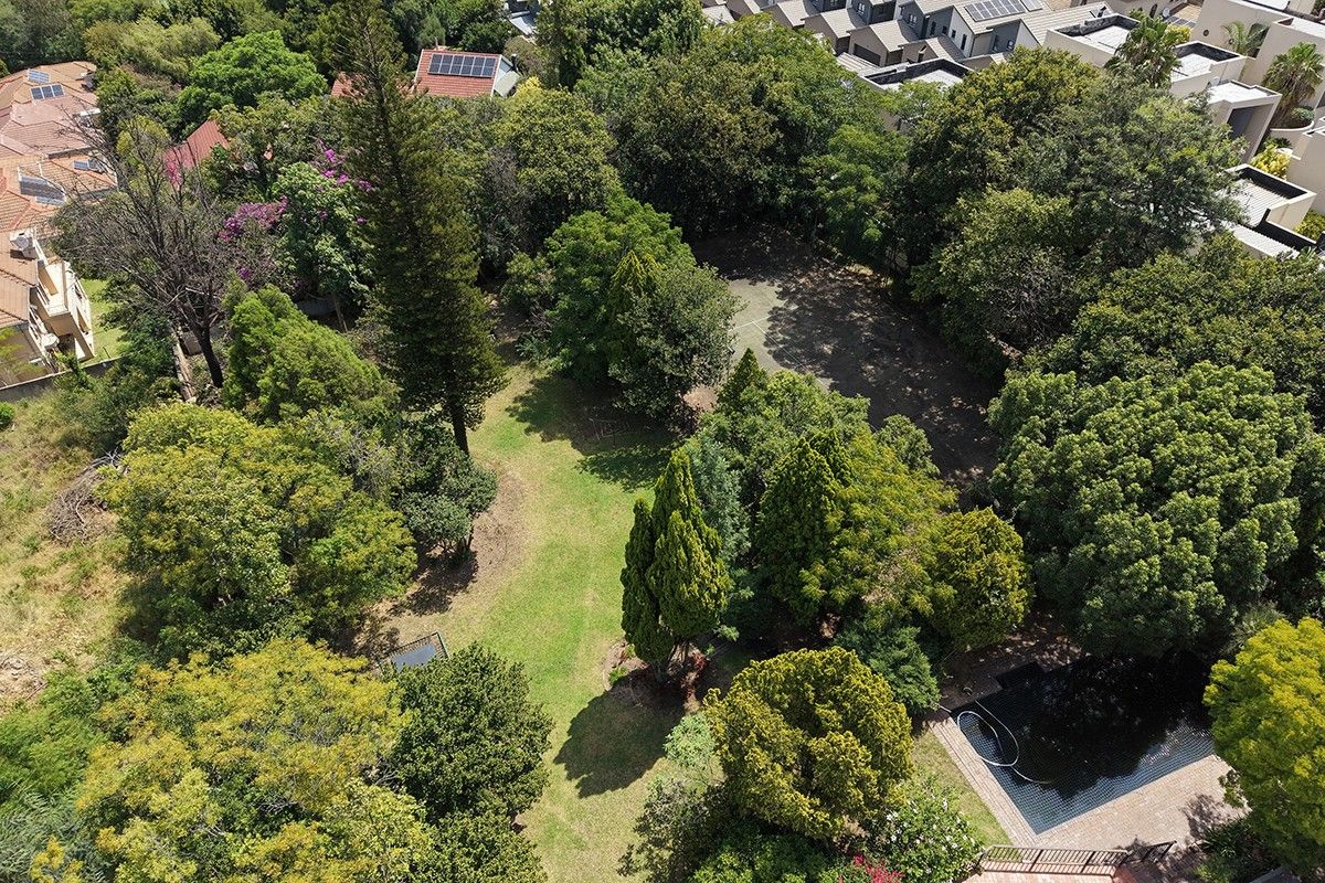 Aerial view of a spacious residential plot featuring established trees, a well-maintained garden, and a swimming pool within a suburban setting.
