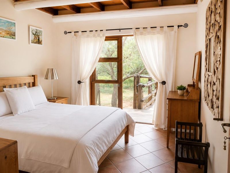 A well-maintained bedroom featuring exposed timber ceiling beams, tiled flooring, and direct access to an outdoor timber deck through a glass door.