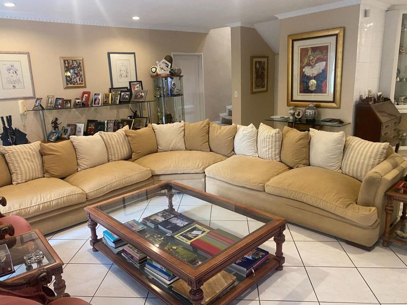 A spacious living room featuring neutral tiled flooring, crown molding, and recessed lighting, providing a comfortable and well-lit area for relaxation.