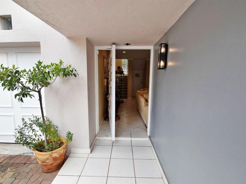 A welcoming entrance area featuring tiled flooring, a modern wall-mounted light fixture, and direct access to the home and garage.