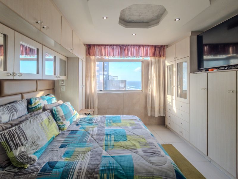 A bedroom featuring extensive built-in cabinetry, recessed ceiling lighting, and tiled flooring, offering functional storage and a view through the window.