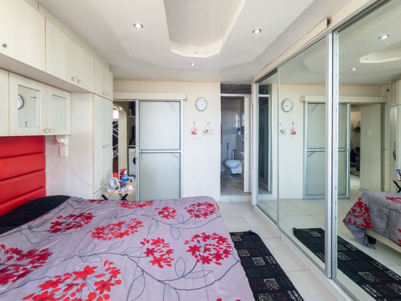 Bedroom featuring extensive built-in cabinetry, mirrored sliding wardrobes, recessed ceiling lighting, tiled floors, and direct access to an en-suite bathroom.