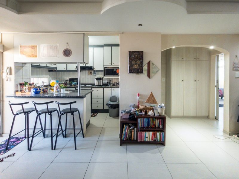 Open-plan kitchen and living area featuring granite countertops, tiled flooring, and built-in cabinetry with a functional layout.