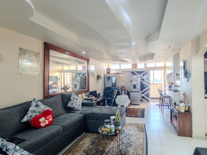 Open plan living and kitchen area featuring tiled flooring, a breakfast bar, and a distinctive recessed ceiling design.