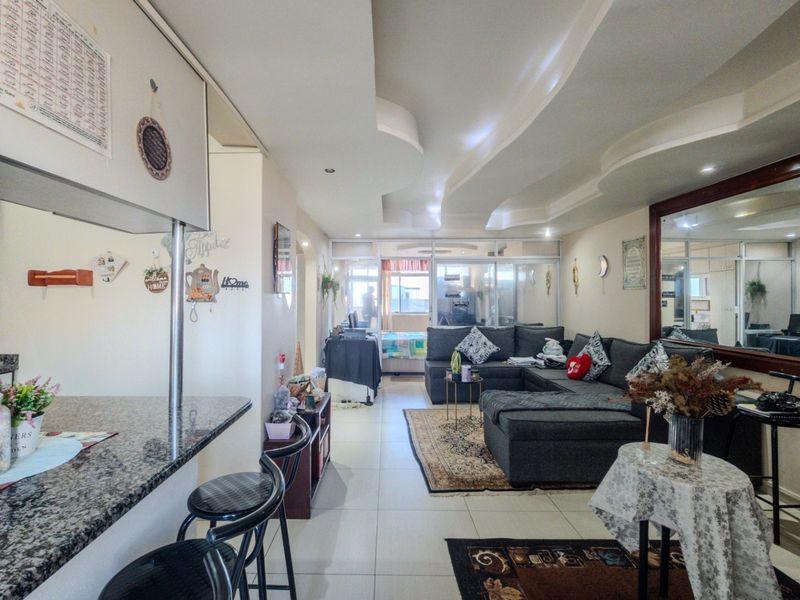 Open-plan living area featuring a granite breakfast bar, tiled flooring, and unique recessed ceiling design, flowing into a secondary partitioned space.
