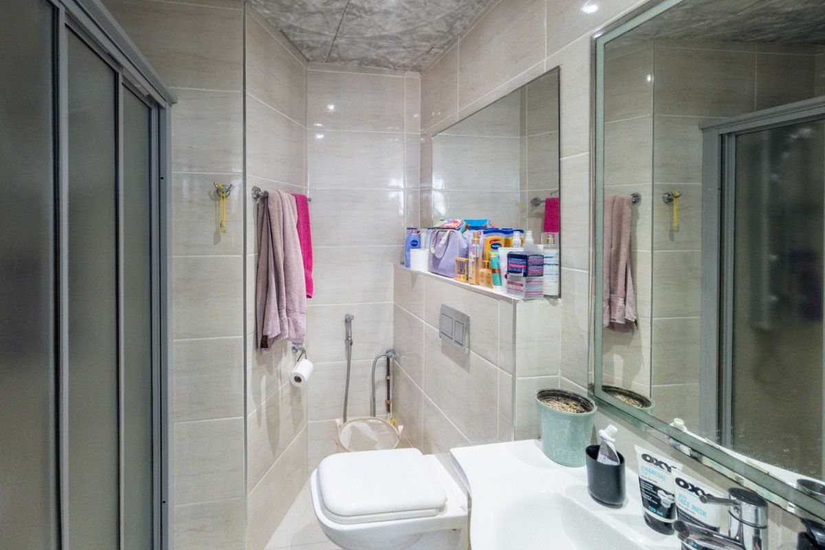 Modern bathroom featuring a wall-mounted toilet with concealed cistern, vanity basin with mixer tap, and a glass shower enclosure with neutral wall tiling.