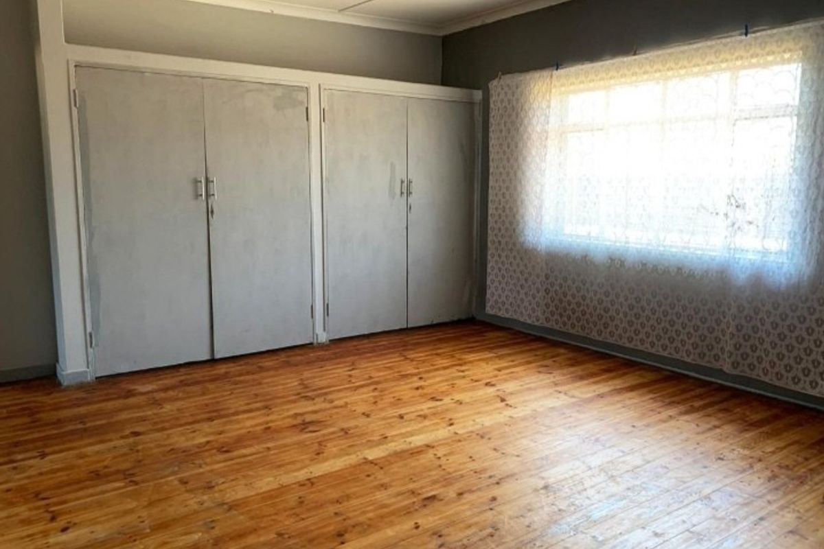 A vacant bedroom featuring original timber flooring and built-in storage cupboards, offering a blank canvas for potential renovation or restyling.