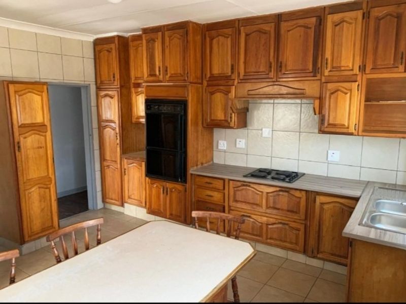 A functional kitchen featuring traditional wooden cabinetry, built-in oven, hob, tiled backsplash, and a double bowl sink with laminate countertops.