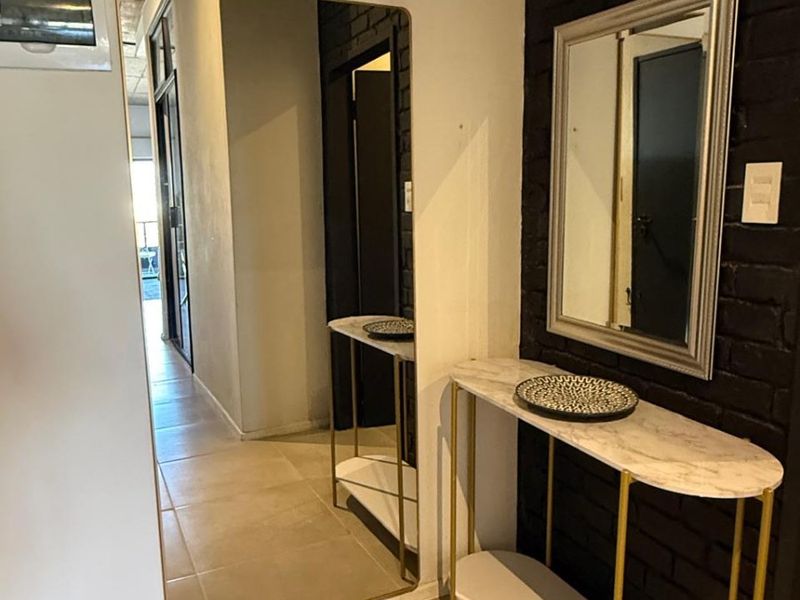 An inviting entryway featuring a textured black brick feature wall and neutral tiled flooring, creating a modern and stylish transition into the apartment.