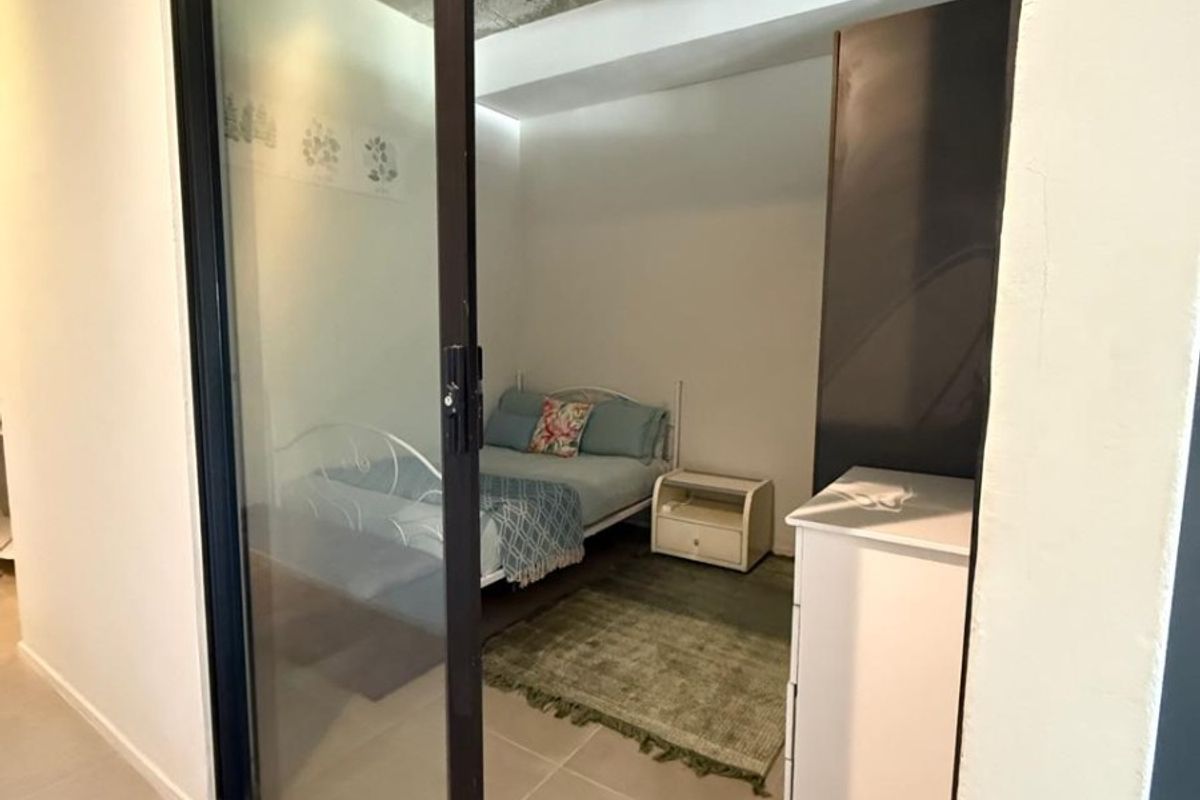 A bedroom featuring an exposed concrete ceiling and a modern black-framed sliding glass door, providing a contemporary industrial aesthetic.