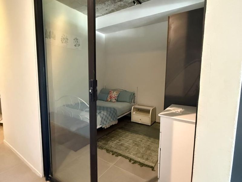 A bedroom featuring an exposed concrete ceiling and a modern black-framed sliding glass door, providing a contemporary industrial aesthetic.