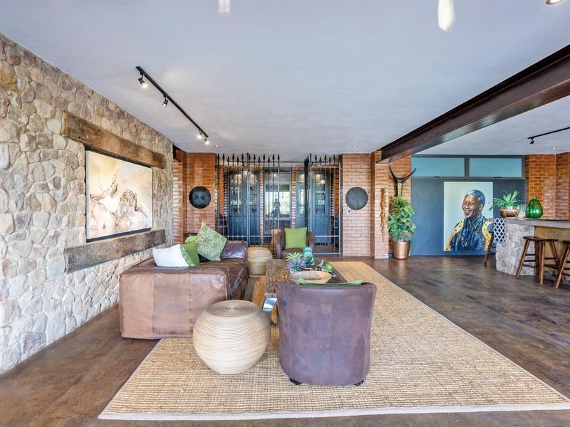 Spacious open-plan living area featuring a stone feature wall, exposed brickwork, steel beam accents, and a built-in bar counter.