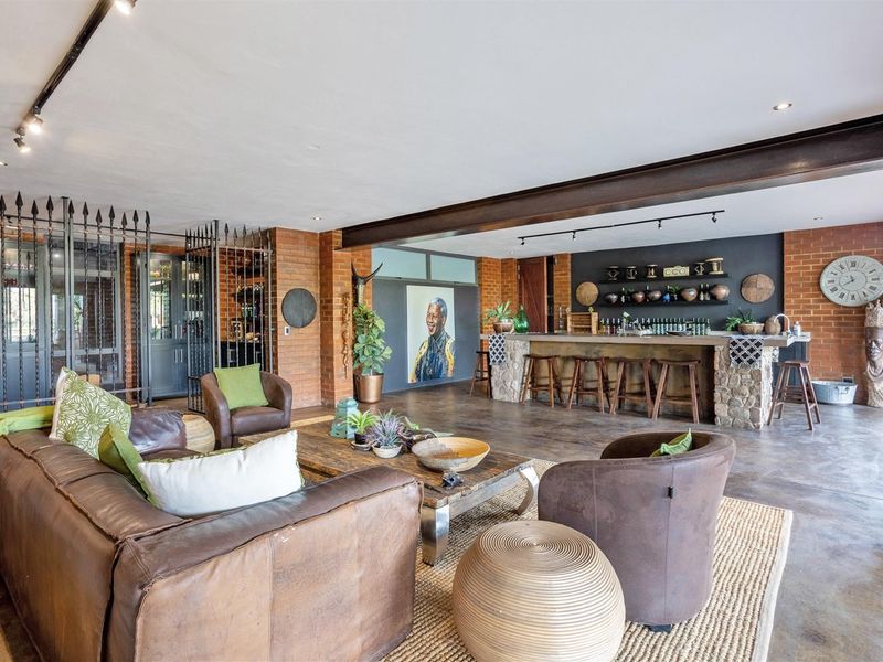 Spacious entertainment area featuring a built-in bar with stone detailing, exposed brick walls, and industrial-style steel beams, creating a rustic and inviting atmosphere.