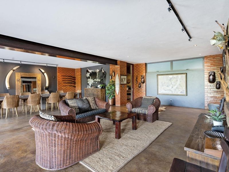 Spacious open-plan living and dining area featuring exposed brick walls, polished concrete floors, and industrial-style steel beam accents with modern track lighting.