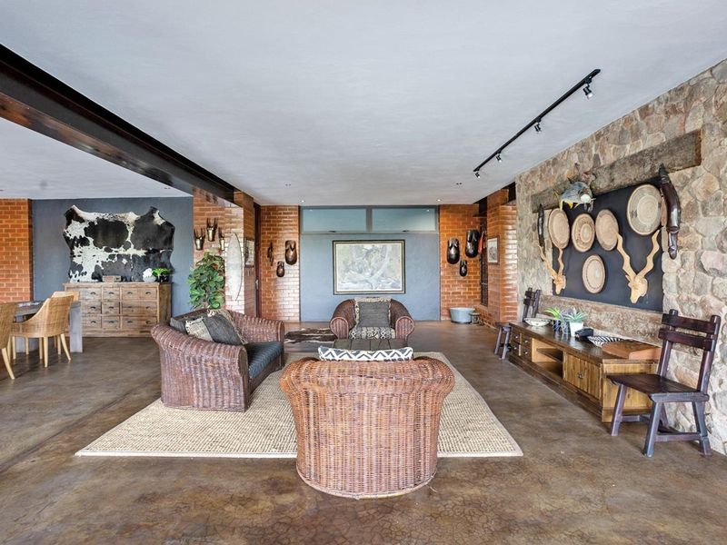 Spacious living area featuring rustic exposed brick and stone walls, polished concrete flooring, and an industrial-style exposed steel beam.