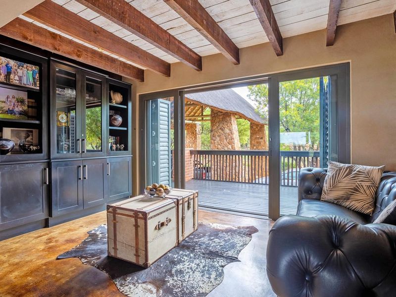 Cozy living room featuring exposed timber ceiling beams, built-in cabinetry, and large sliding doors opening onto a wooden deck.