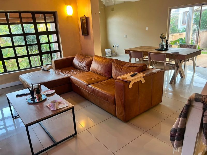 Spacious open-plan living and dining area featuring large windows, tiled flooring, and direct access to the outdoor patio area.