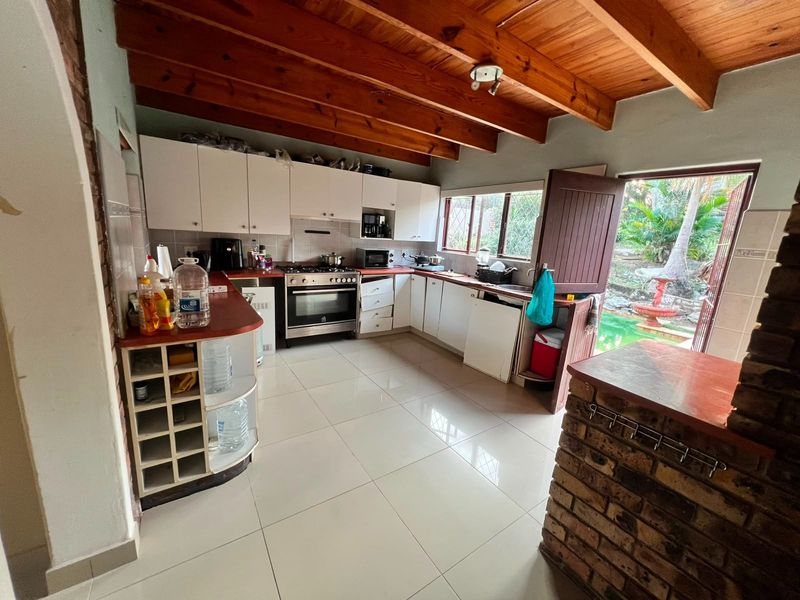 Kitchen featuring exposed timber beam ceilings, tiled flooring, built-in cabinetry, and a brick breakfast bar with direct access to the outdoor pool area.