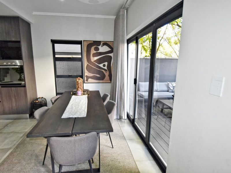 Modern open-plan dining area featuring sleek cabinetry, built-in oven, and large sliding glass doors providing seamless access to the outdoor patio.