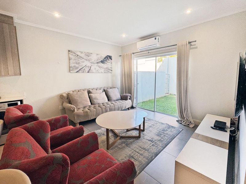 Open-plan living area featuring tiled floors, recessed lighting, a split-system air conditioner, and sliding glass doors providing direct access to the rear garden.