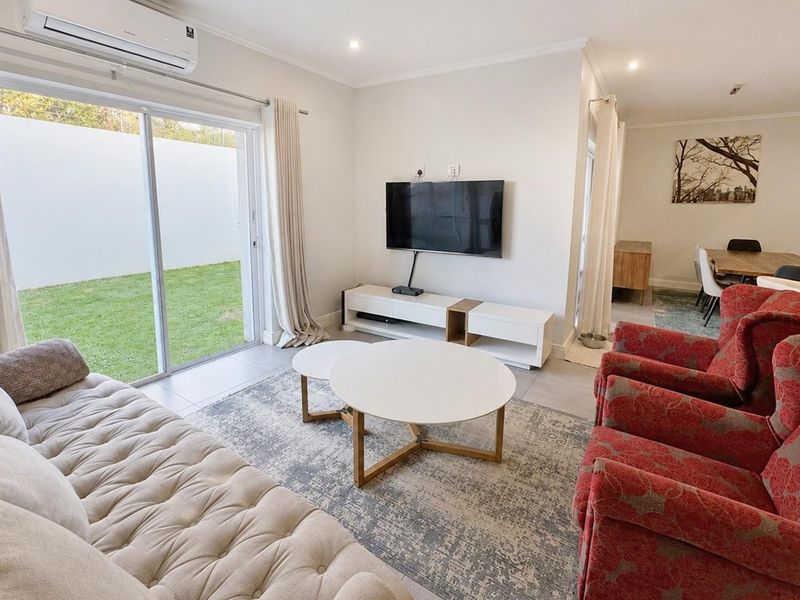 Bright open-plan living area featuring tiled floors, recessed lighting, and a large sliding glass door providing direct access to the rear garden.