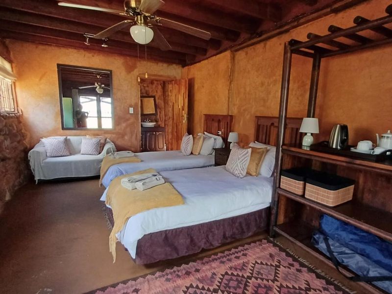 Rustic bedroom featuring exposed timber ceiling beams, textured plaster walls, and an en-suite vanity area.