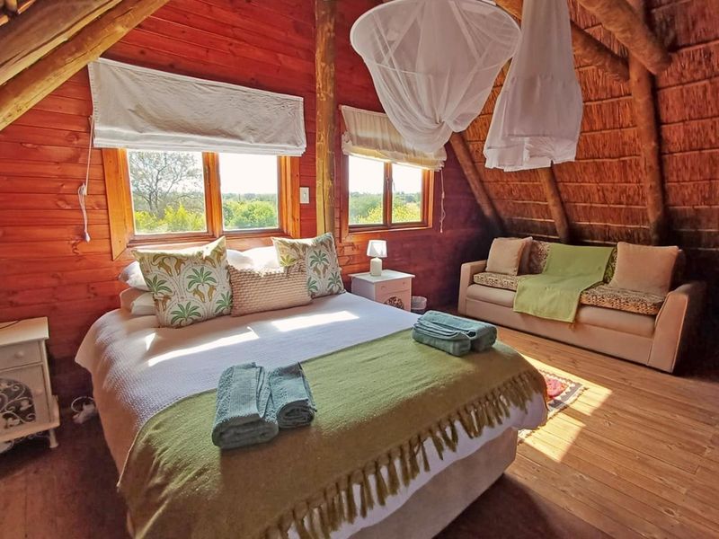 A rustic bedroom featuring exposed timber beams, wood-paneled walls, and a traditional thatched roof ceiling, creating a warm and cozy atmosphere.
