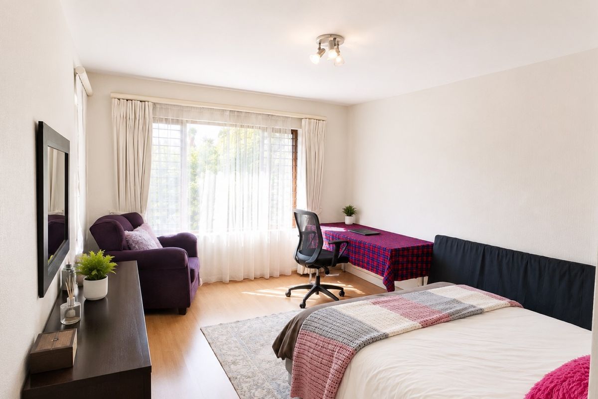 A well-lit bedroom featuring laminate flooring, large windows with security bars, and a neutral color palette.