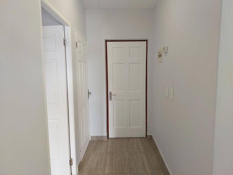 A clean and well-maintained interior hallway featuring neutral tiled flooring and multiple panelled doors providing access to adjacent rooms.