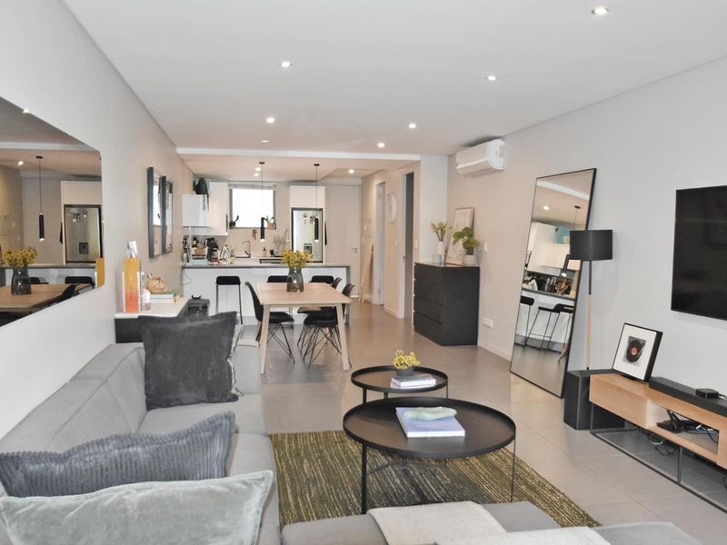 Modern open-plan living and dining area featuring tiled floors, recessed lighting, and a sleek kitchen with a breakfast island and integrated cabinetry.