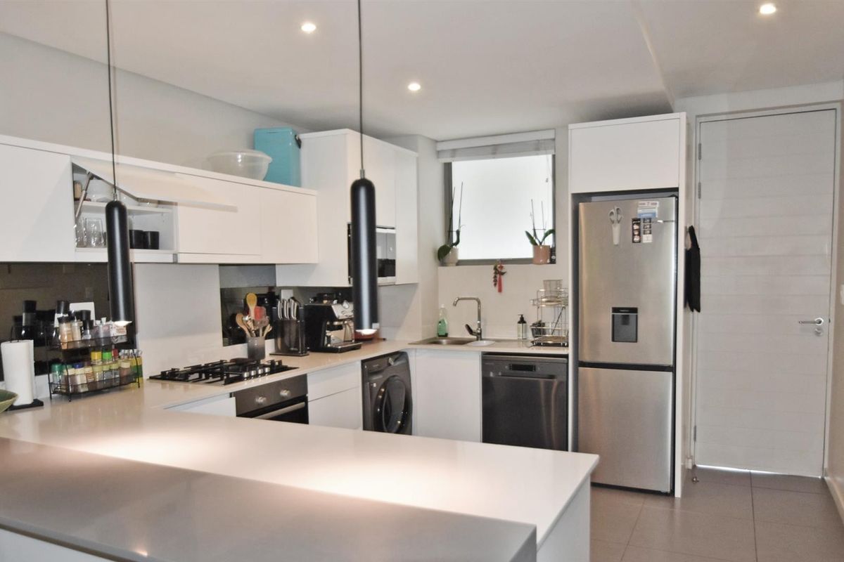 Modern kitchen featuring white cabinetry, stone countertops, integrated appliances, gas hob, and recessed lighting in a clean, functional layout.