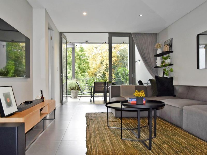Modern living room featuring tiled floors, recessed lighting, and large sliding glass doors providing seamless access to an outdoor balcony area.