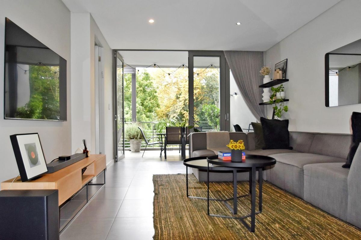 Modern living room featuring tiled floors, recessed lighting, and large sliding glass doors providing seamless access to an outdoor balcony area.