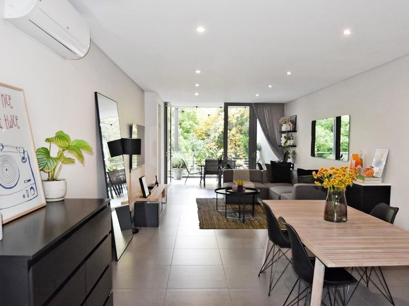 Spacious open-plan living and dining area featuring neutral tiled flooring, recessed lighting, and direct access to a private balcony through large sliding glass doors.