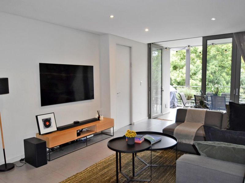 Modern living room featuring tiled floors, recessed lighting, and large sliding glass doors providing seamless access to an outdoor balcony area.