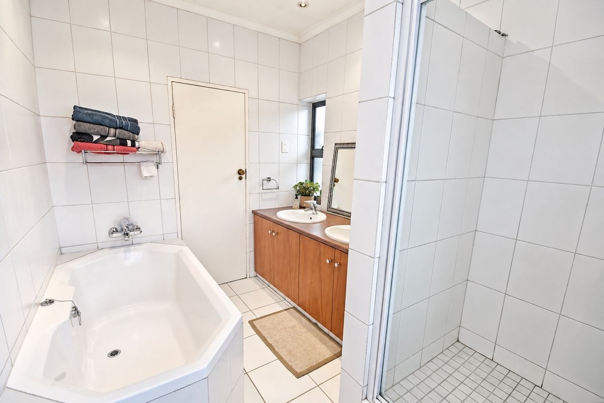 A functional bathroom featuring a built-in vanity with dual basins, a separate bathtub, and a tiled shower enclosure.