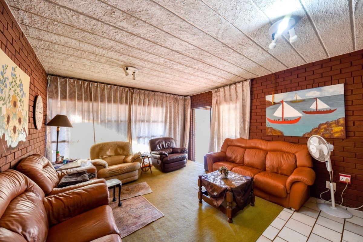 Spacious living room featuring exposed brick walls, textured ceiling tiles, and direct access to the outdoors through a sliding glass door.