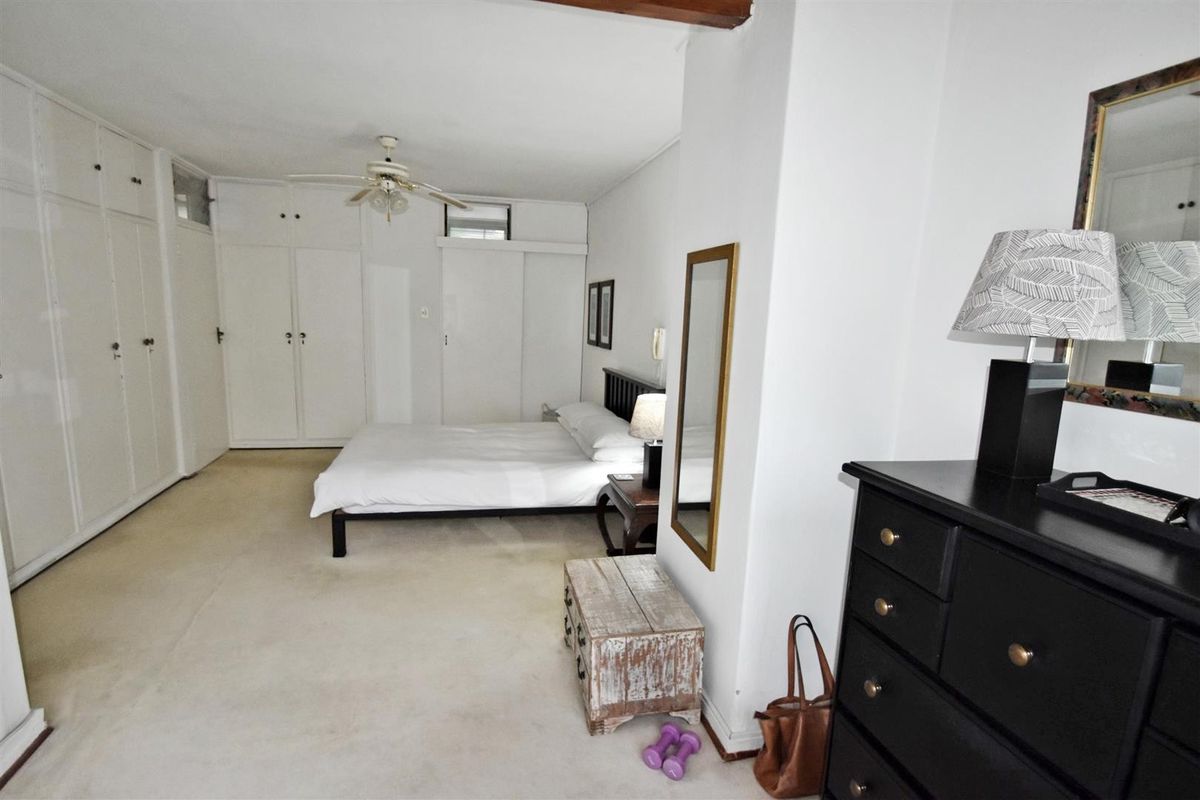 Spacious bedroom featuring extensive built-in cupboard storage and a ceiling fan, offering a neutral canvas for personalization.